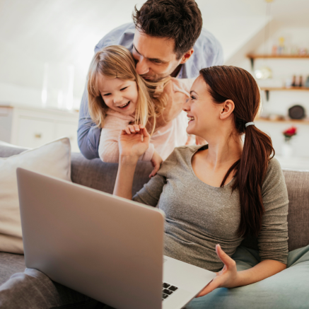 Family laughing while looking at laptop