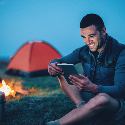 Person-Camping-Looking-at-Phone-With-Fire-in-the-background